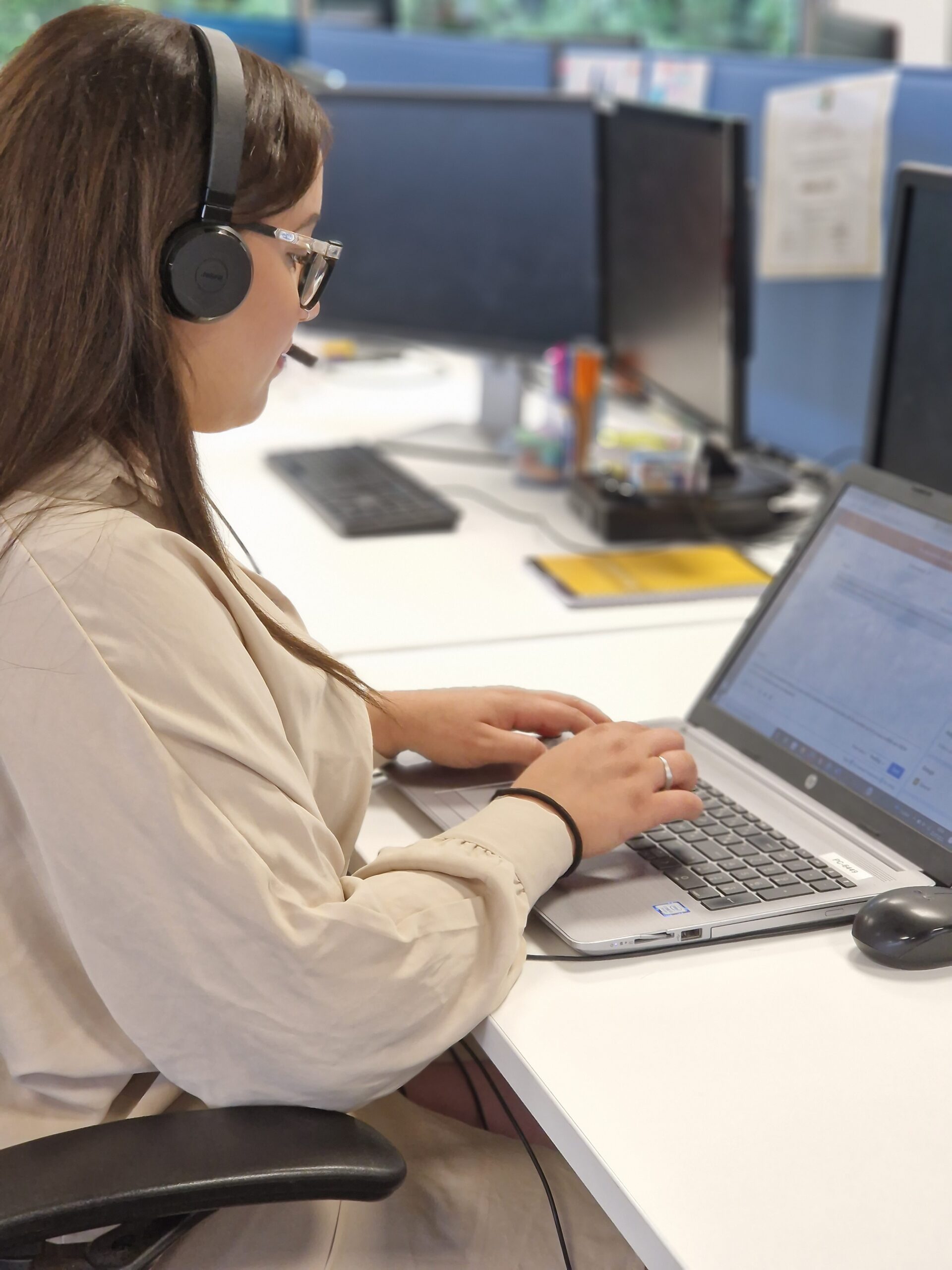 Une femme est assise à son bureau devant un ordinateur avec un casque aux oreilles